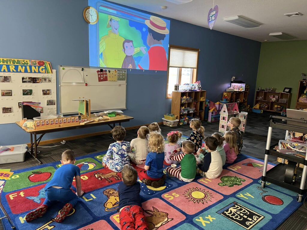 Group of preschool students watching Curious George